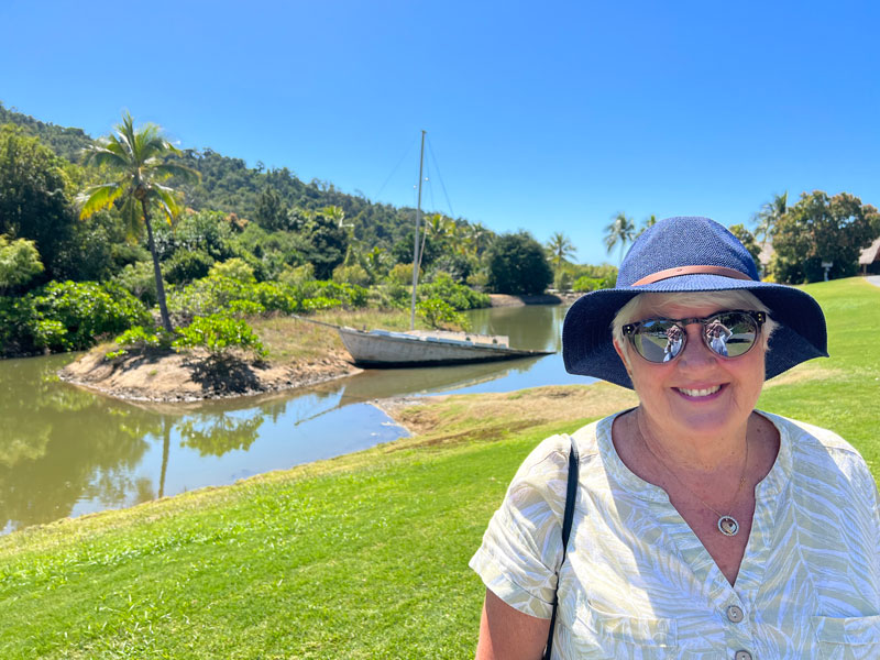 Sue standing on a grassy riverbank